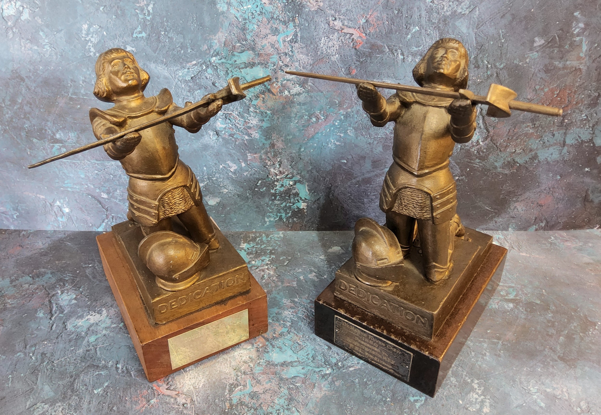 A near pair of Dedication figural trophies, holding a sword aloft on a wooden plinth base.
