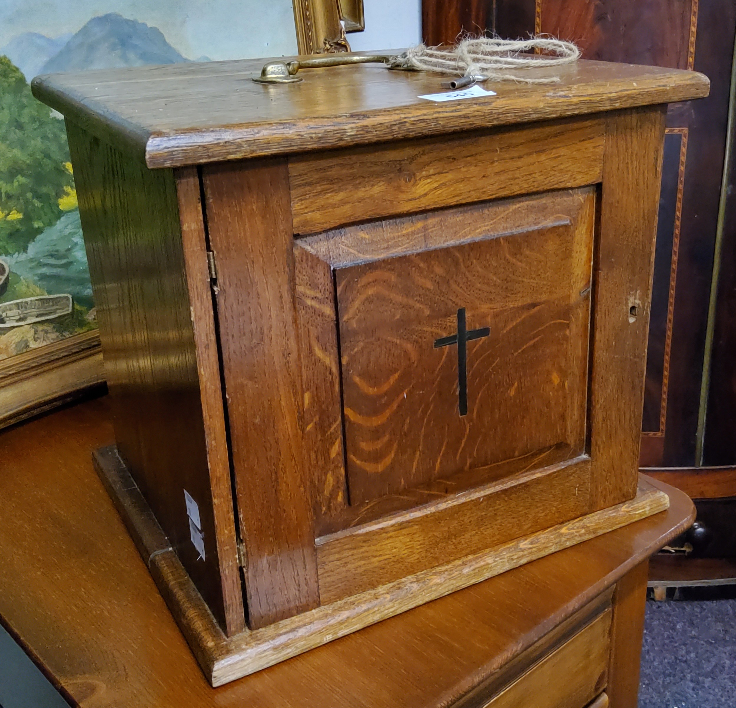 An early 20th century oak ecclesiastical alter cabinet, panelled door, inlaid with a cross, brass