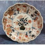 A Japanese Imari shaped circular plate, decorated with jardinere and chrysanthemums, the sides