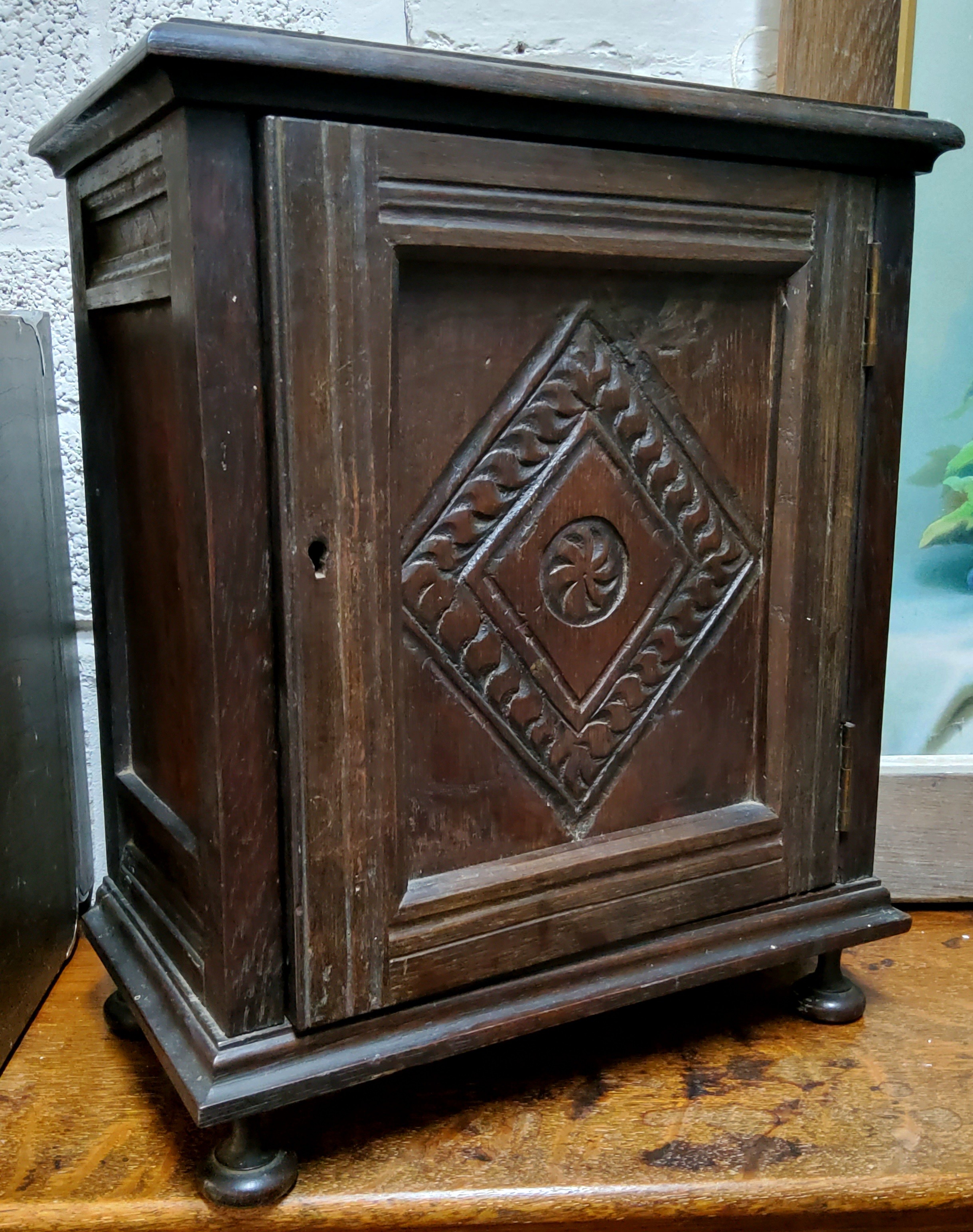 An early 20th century oak table top, smokers cabinet, carved ;lozenge panelled door, fitted
