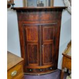 WITHDRAWN - A George III country house bow front  mahogany corner cupboard, barber pole strung