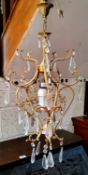 A 20th century gilt metal ceiling light, cast with leafy scrolls, prismatic clear glass lustres,