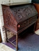 A late 19th / early 20th century carved padouk wood scholar's bureau on stand, profusely carved with