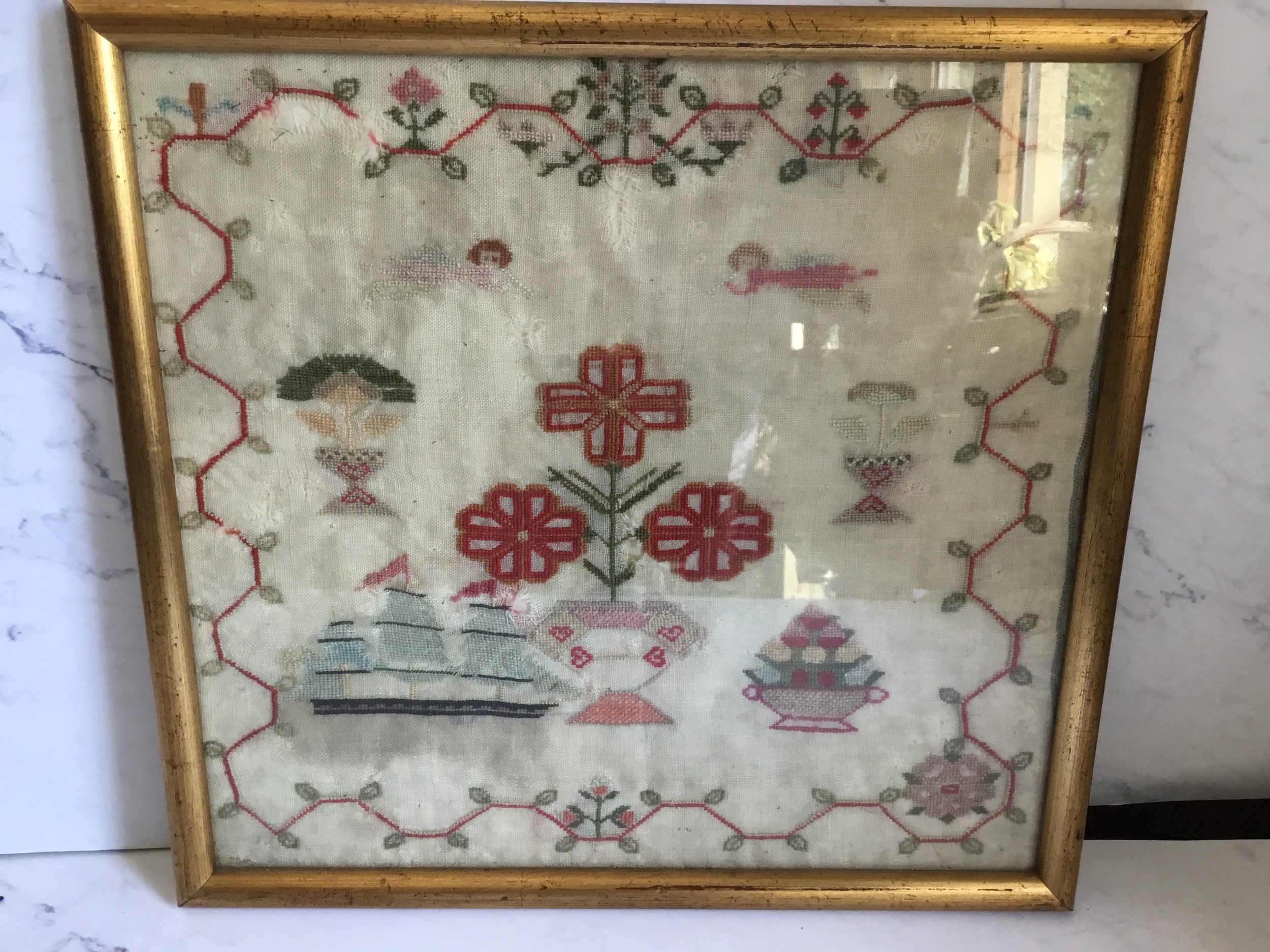 A Victorian Marine needlework sampler, embroidered with 3 masted ship, stylised flowers and
