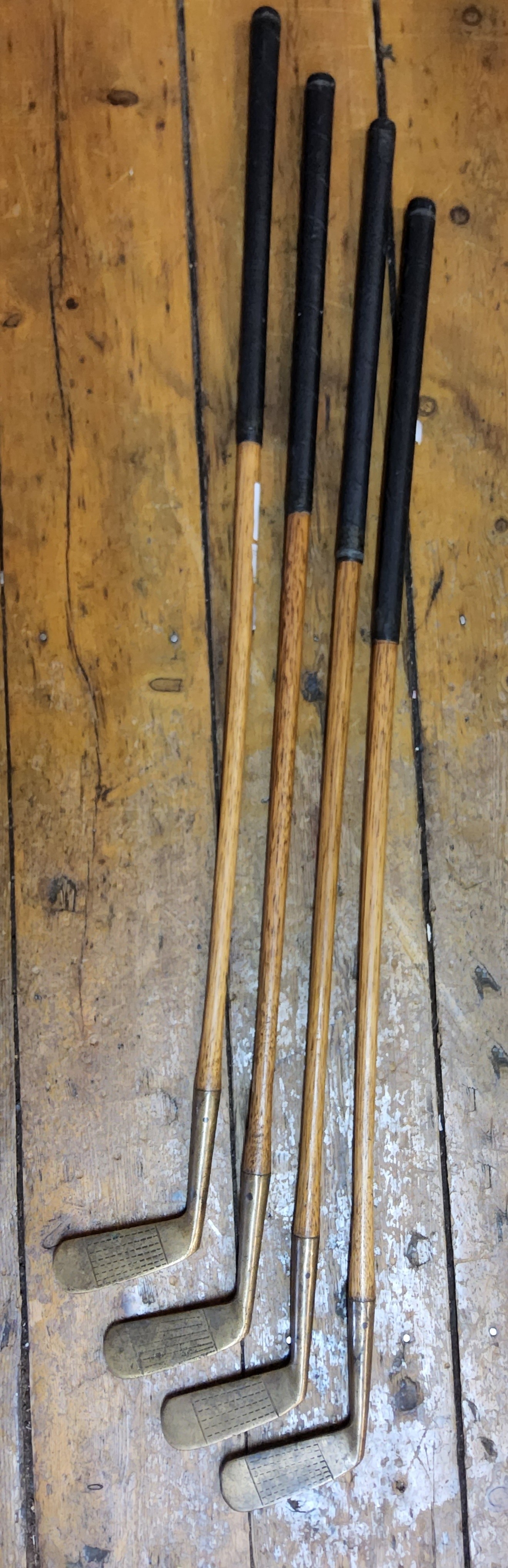 Early Golfing Interest- a set of four Edwardian hickory shafted and brass putter golf clubs, each