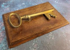 A late 19th century novelty desk letter clip, in the form of key,  oak rectangular base, 25cm