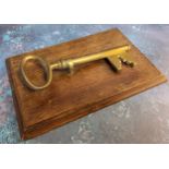 A late 19th century novelty desk letter clip, in the form of key,  oak rectangular base, 25cm