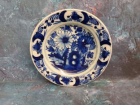An 18th century Dutch Delft plate, decorated in underglazed blue with stylised flowers and fence,