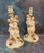 A pair of German figural candlesticks, of a maiden and cherub, floral encrusted bases, 31cm high,