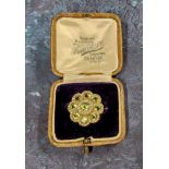 An unusual yellow brooch in the form of a flower head, set with nine round peridots and seed pearls,