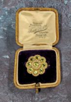 An unusual yellow brooch in the form of a flower head, set with nine round peridots and seed pearls,