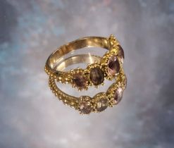An early Victorian yellow metal etruscan style trilogy ring, set with five graduated pink topaz oval