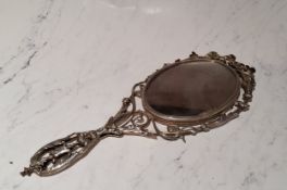 An unusual silver coloured metal hand mirror, cast and pierced with scrolling foliage, the back