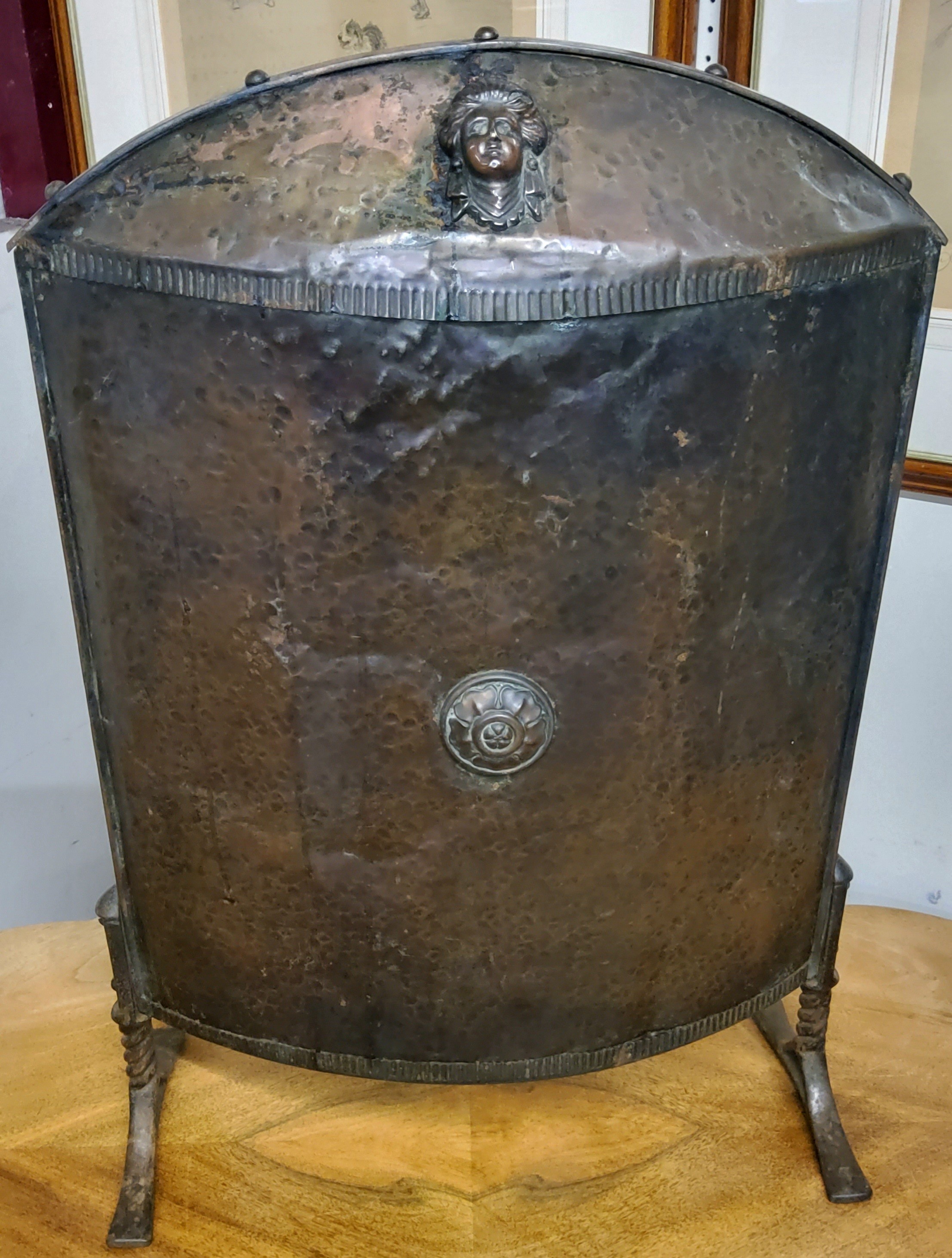 An early 20th century Empire taste fire guard,  arched and domed beaten copper, Etruscan mask detail