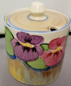 A Clarice Cliff Pansy pattern cylindrical preserve pot and cover, painted with pansies above a