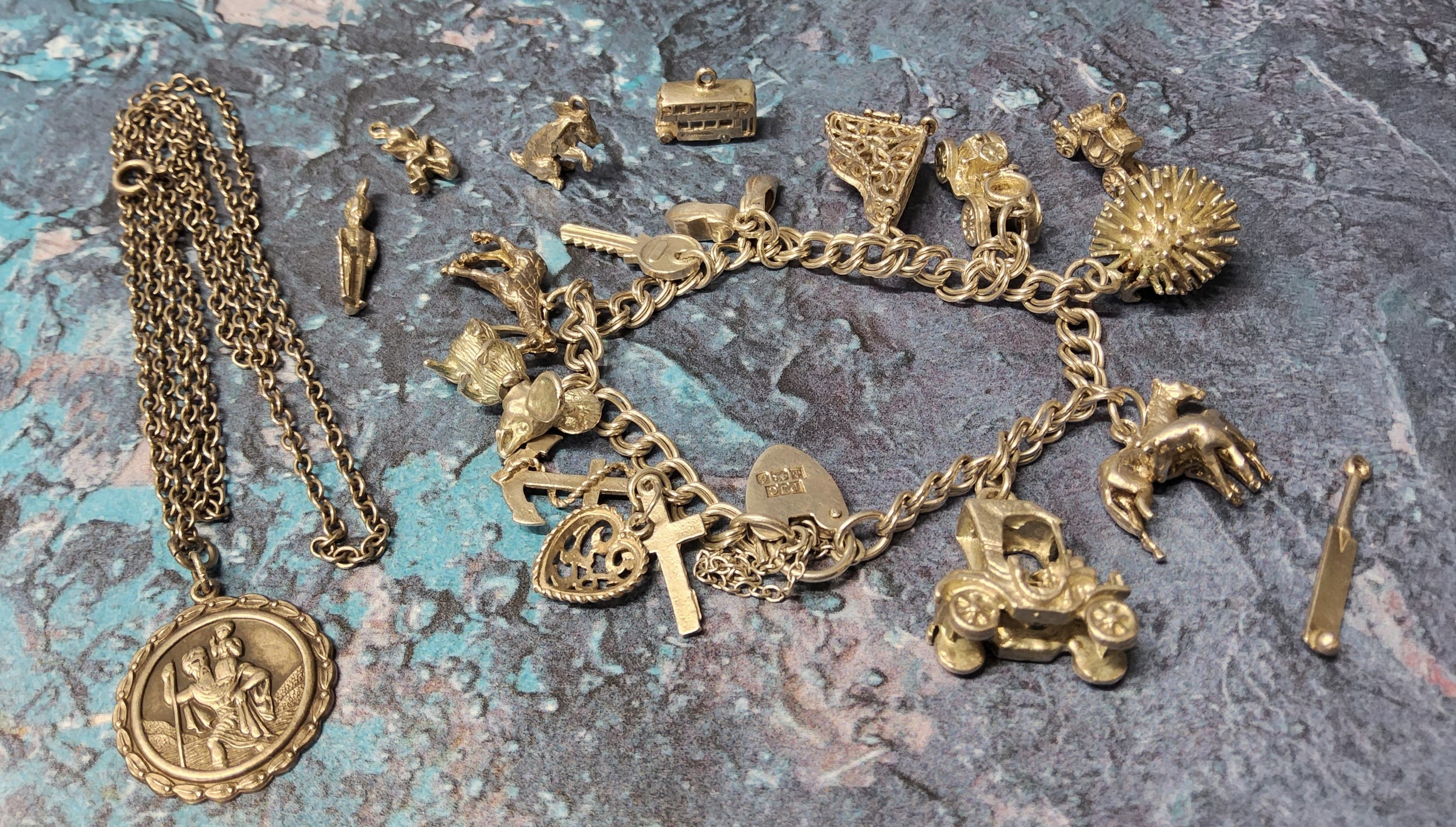 A silver charm bracelet holding 10 charms including a horse & foal, grand piano, mouse etc. other