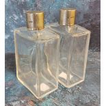 A pair of George V silver and clear glass scent flasks, the covers engine turned, 12.75cm high,