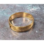 A 9ct gold hinged bangle, chased & engraved with foliate scrolls, (it does not have a metal core)
