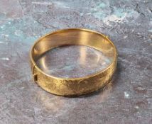 A 9ct gold hinged bangle, chased & engraved with foliate scrolls, (it does not have a metal core)