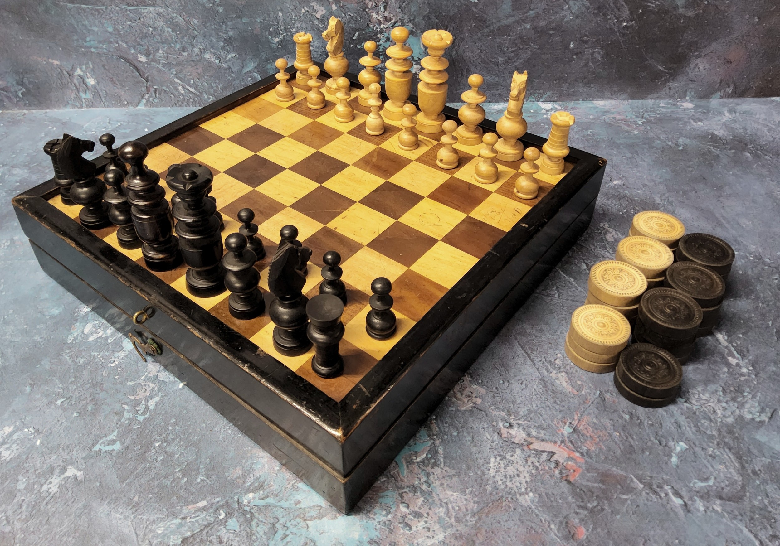 An early 20th century travelling games box, the cover inlaid with chess board, the interior for