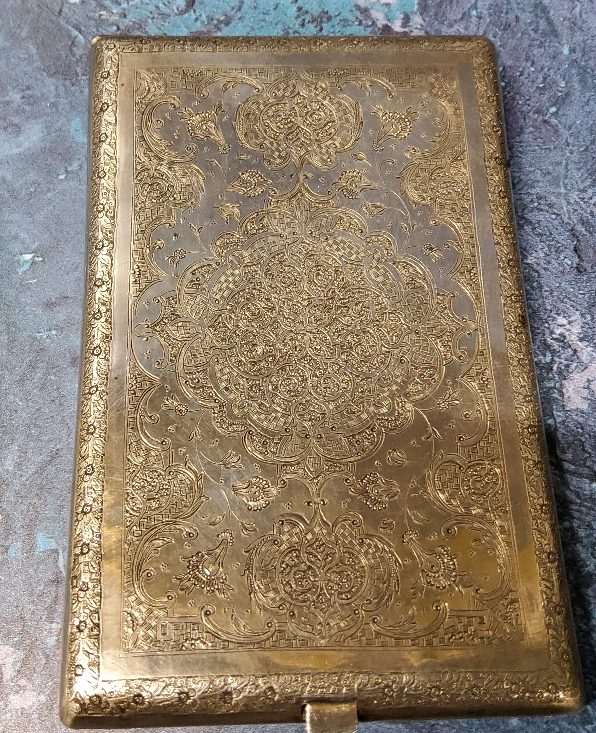 An Islamic silver coloured metal bowed rectangular card case, engraved overall with animals, birds