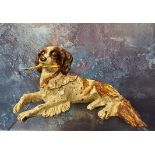 A cold painted bronze novelty pen nib box, in the form of a reclining terrier, holding a feather,