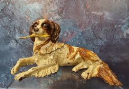 A cold painted bronze novelty pen nib box, in the form of a reclining terrier, holding a feather,
