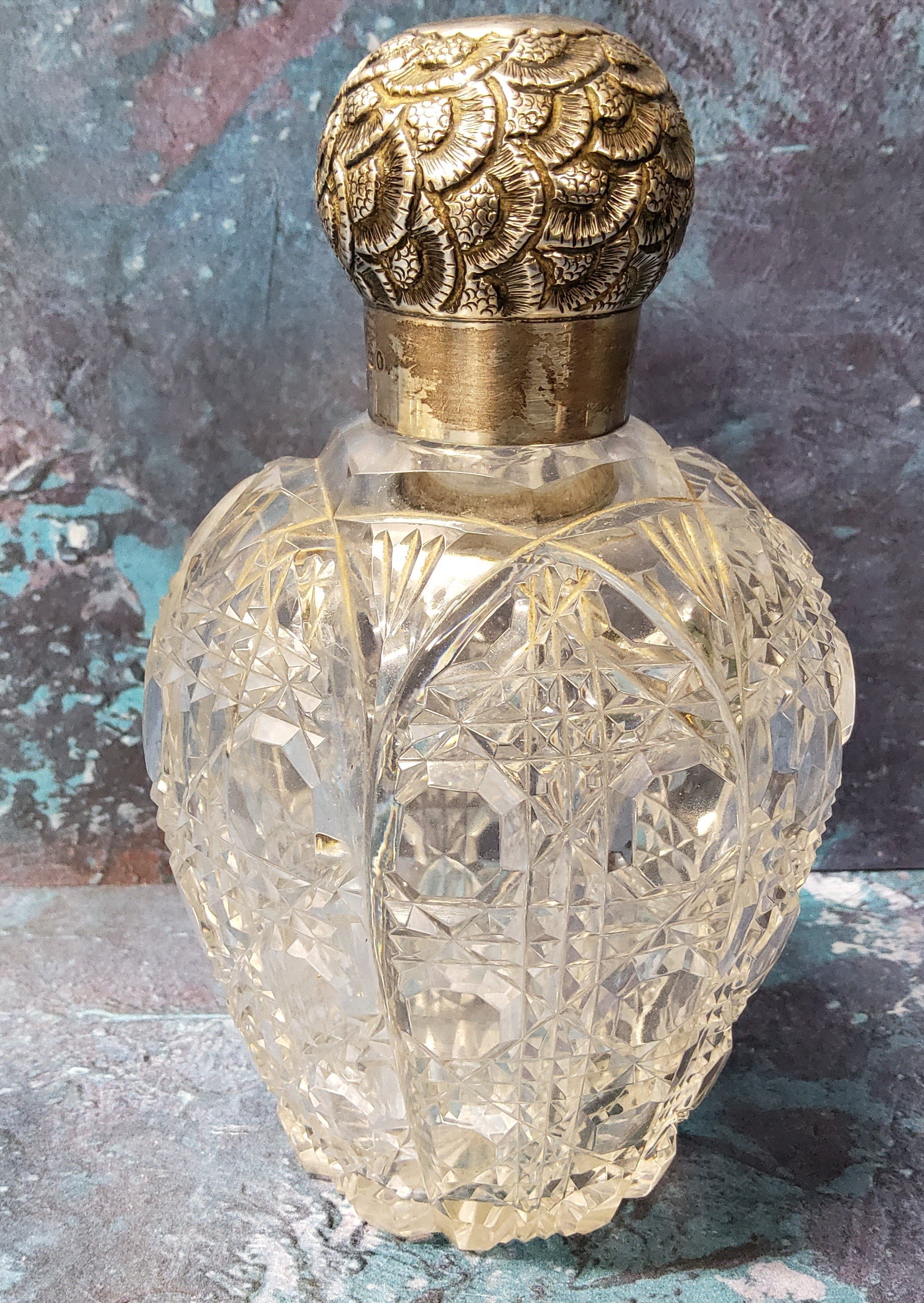 A large Victorian clear cut glass and silver scent bottle, the screw-off cover embossed with