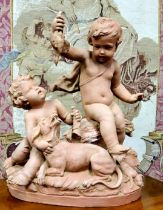 A good Continental terracotta group, depicting two cherubs tormenting a dog, holding a bird in their