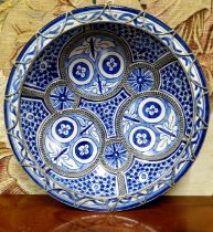 An Islamic pottery and  white metal mounted charger, decorated in underglaze blue with stylised