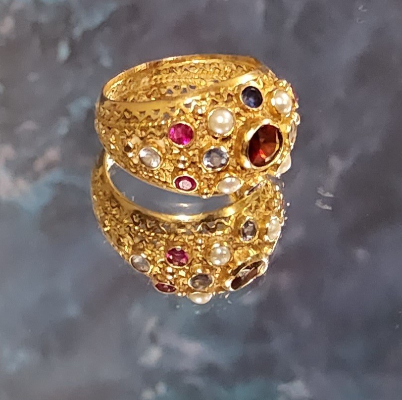 An 18ct gold Indian style cluster ring, collet set with rubies, sapphires & seed pearls, pierce work