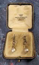 A pair of Art Deco diamond & pearl drop earrings, a brilliant cut diamond, rub set in a plain