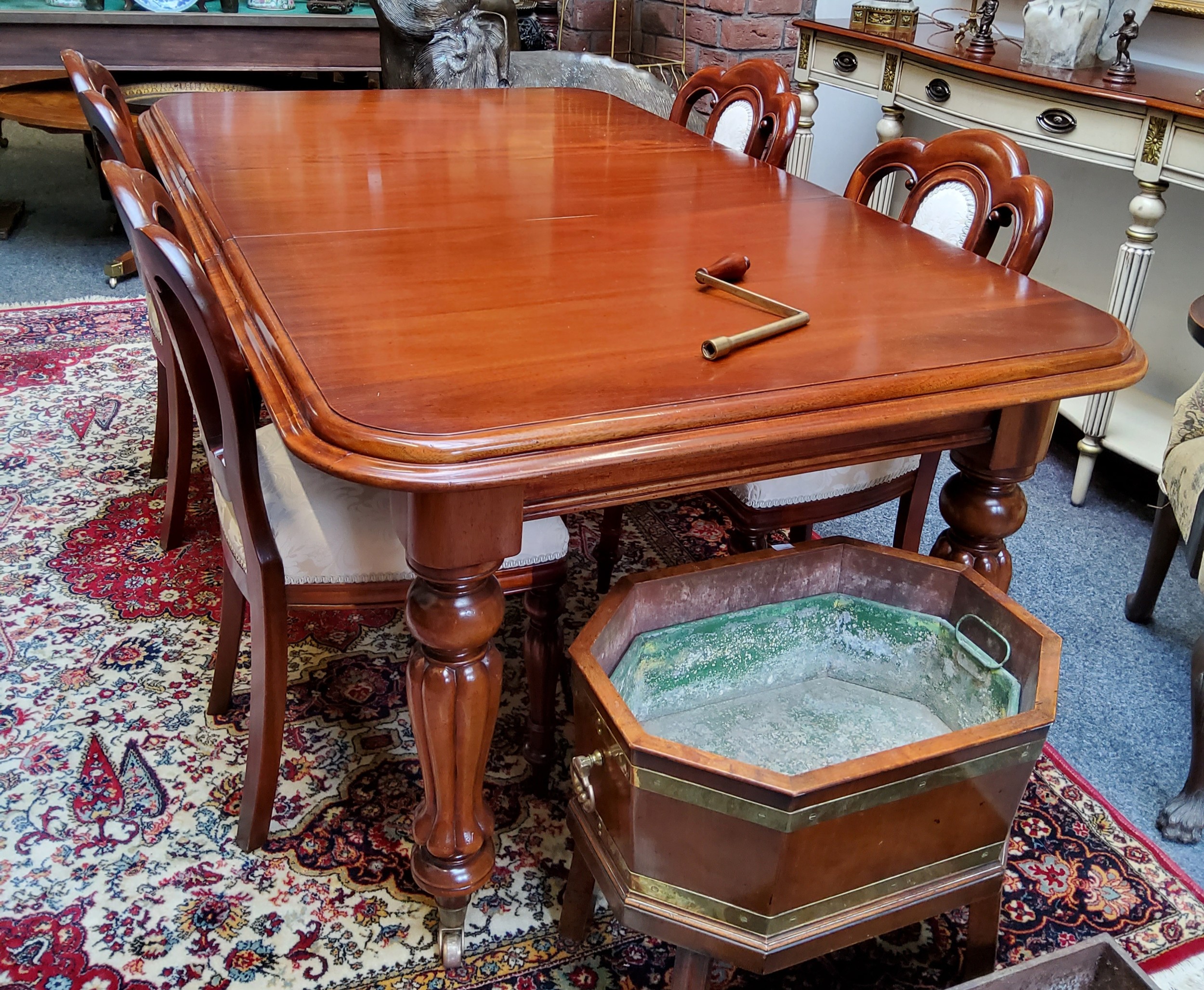 A clean Victorian style dining table, boldly turned and reeded legs terminating on castors; four