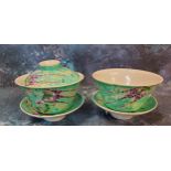 A pair of Chinese tea bowls and stands, one with cover, decorated with birds, flowers and foliage on