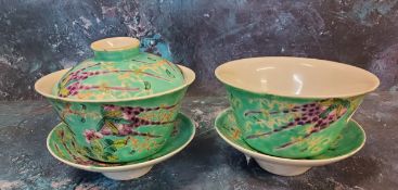 A pair of Chinese tea bowls and stands, one with cover, decorated with birds, flowers and foliage on