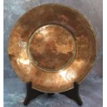 An Indian copper circular dish, engraved with alternate leaves and symbols, 28cm wide