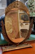 A large Middle Eastern copper dressing table mirror, profusely embossed in relief and chased with