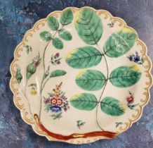 A Worcester Blind Earl pattern shaped circular plate, in relief with leaves and buds, painted with