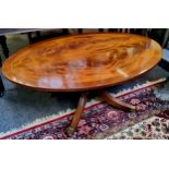 A very clean quarter veneered flamed mahogany oval coffee table, raised on four outswept fluted legs