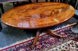 A very clean quarter veneered flamed mahogany oval coffee table, raised on four outswept fluted legs