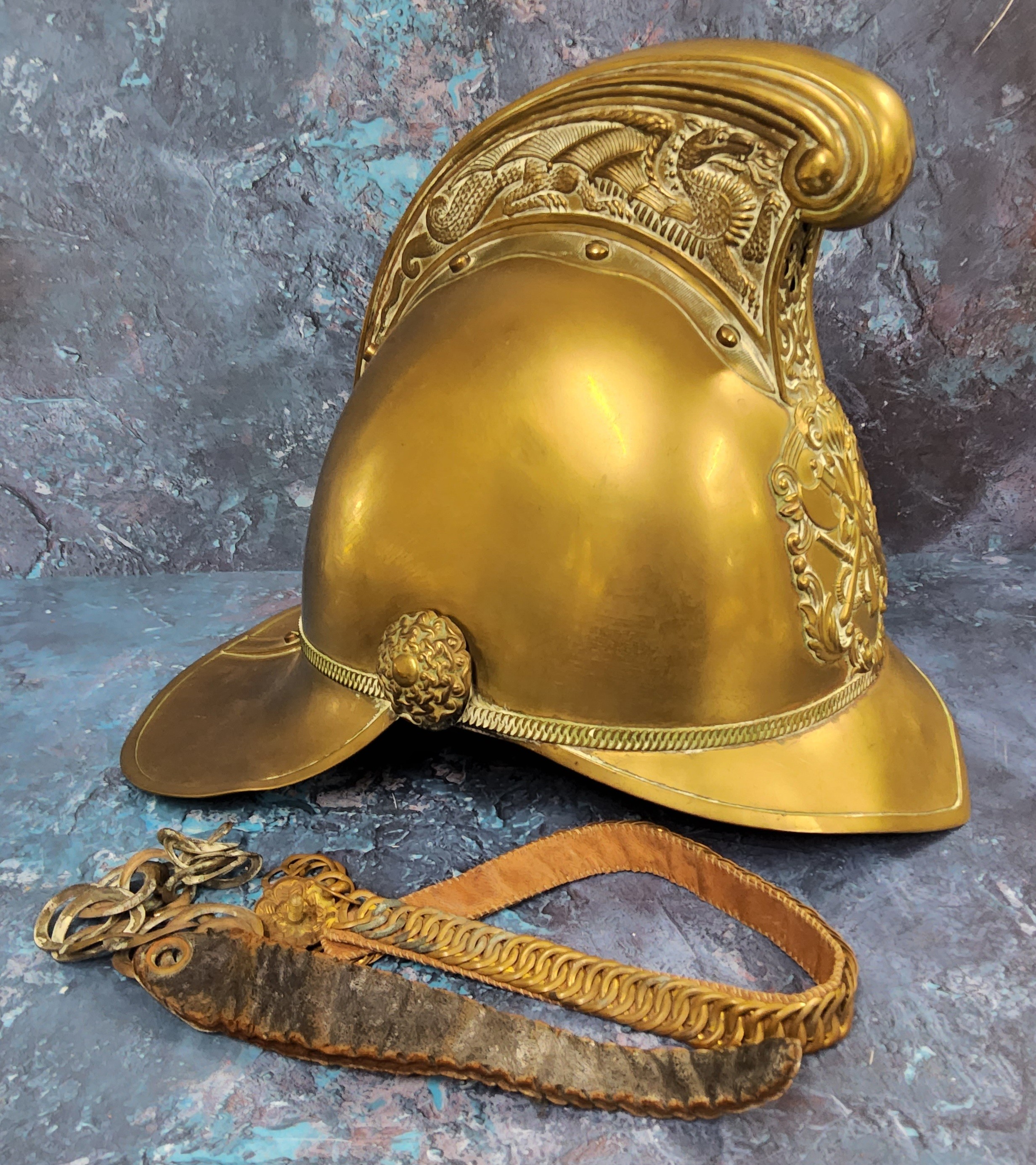 A Victorian brass Merryweather fireman's helmet, ornate high comb, applied with emblem, leather