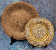 An Indian circular copper dish, applied in silver with scrolls, 29.5cm diam; another, smaller, the