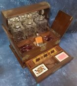 A late Victorian oak tantalus cabinet, three hobnail cut  decanters, hinged twin covers enclosing