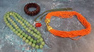 A cherry amber bracelet, 44g;  a single bead, 4g;   a 'Jade' necklace, 90cm long;  another, 40cm