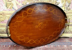 An early 20th century oval mahogany two handled tray, with musical trophies within a entwined