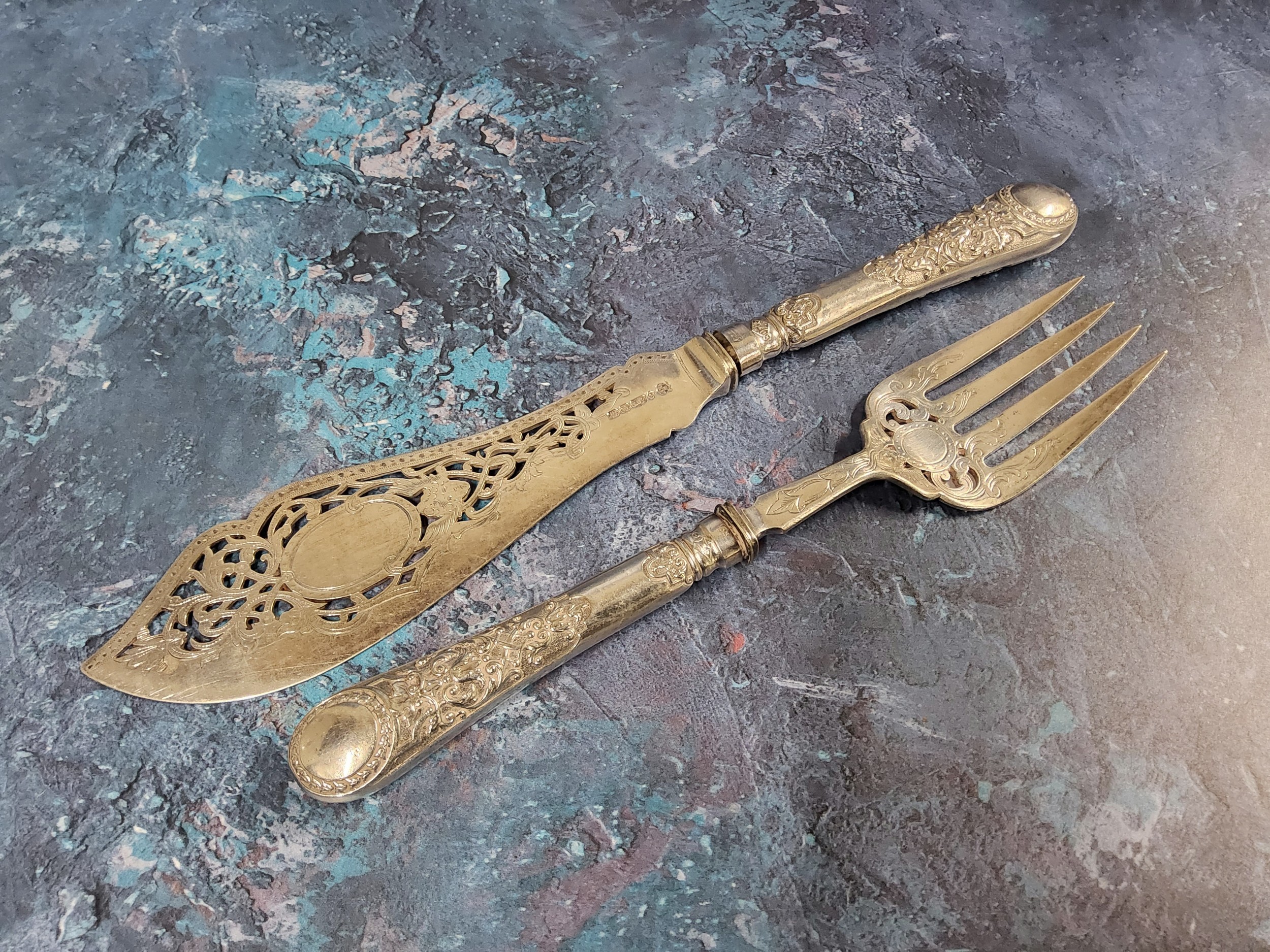 A pair of Victorian E.P.N.S. fish servers, the blades pierced and engraved with scrolling foliage,