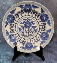 A Chinese shaped circular plate, painted in underglaze blue with stylised peonies, 25.5cm diam,