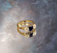 An 18ct gold sapphire & diamond trilogy ring, the claw set emerald cut sapphire 6 x 5mm flanked by