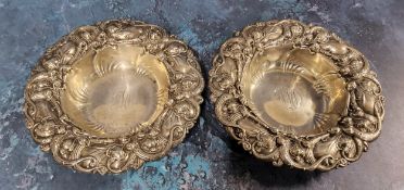 A pair of American Art Nouveau sterling silver shaped circular dishes, embossed with scrolling