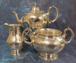A silver three piece tea service, of ovoid from, engraved with circular vacant cartouche, surrounded